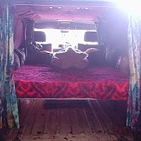 in the back, shows stowage under bed, bed can also be droped down to floor level, its on telescopic legs,
comes out 2 so bigger stuff can be transported